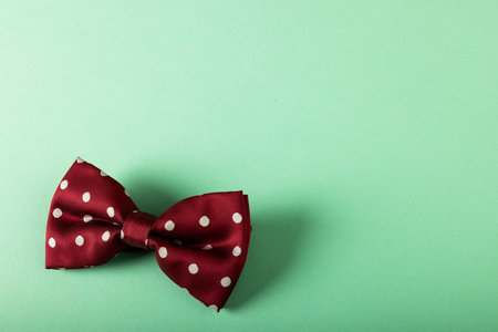 High angle view of maroon bowtie with white polka dots isolated on blue background, copy space. Menswear, fashion, elegance concept.の写真素材