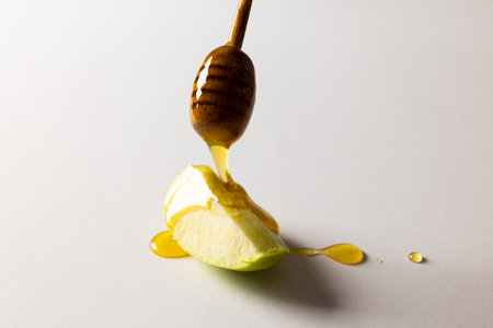 Close-up of honey dipping on granny smith apple slice over white background, copy space. sweet food, fruit, food, healthy and autumn season concept.の写真素材