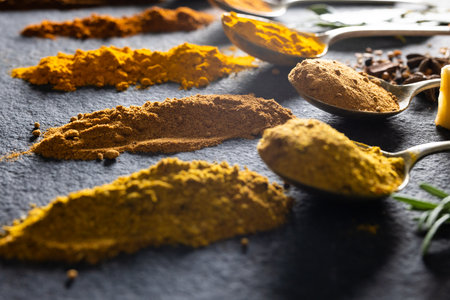 High angle view of spoons with various ground spices on black marble table. unaltered, food, ingredient and seasoning concept.の写真素材