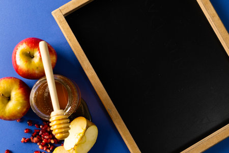 Directly above shot of writing slate with honey, apples and pomegranate on blue background. copy space, education, learning, sweet food, fruit, food, healthy and autumn season concept.の写真素材