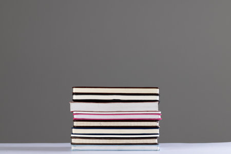 Close up of stack of books and notebooks with copy space on grey background. Reading, learning,...