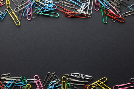 Close up of stack of multi coloured paper clips and copy space on black background. School materials, organising, learning, school and education concept.の写真素材