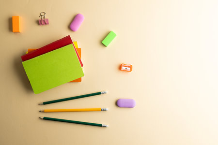 Flat lay of pencils, memo notes, sharpener and erasers with copy space on yellow background. School...