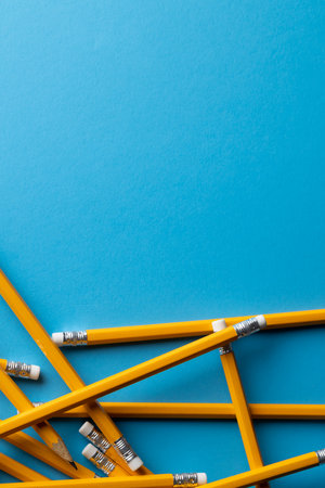 Close up of stack of yellow pencils with erasers and copy space on blue background. Writing, drawing, learning, school and education concept.の写真素材