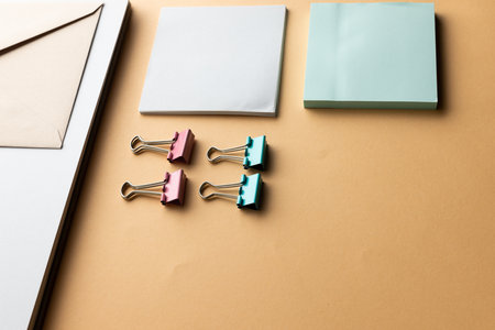 Flat lay of envelope, paper clips and memo notes with copy space on yellow background. School...