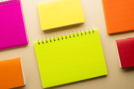 Multi coloured notebooks and copy space on orange background. Reading, learning, school and...
