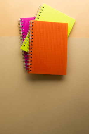 Multi coloured notebooks and copy space on orange background. Reading, learning, school and education concept.の写真素材