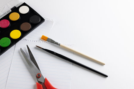 Close up of paints, paper, scissors and brushes with copy space on white background. Back to school, art, painting, school materials, learning, school and education concept.の写真素材