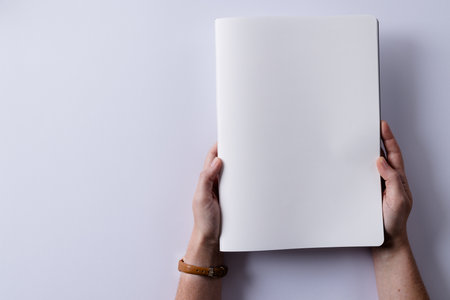 Hands of caucasian woman holding book with copy space on white background. Literature, reading, leisure time and books.の写真素材