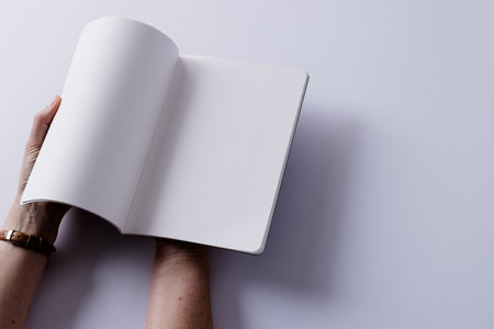 Hands of caucasian woman holding book with copy space on white background. Literature, reading, leisure time and books.の写真素材