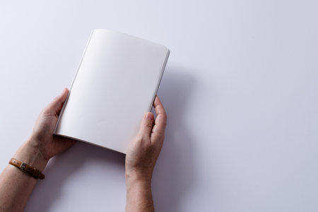 Hands of caucasian woman holding book with copy space on white background. Literature, reading, leisure time and books.の写真素材