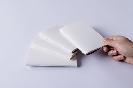 Hand of caucasian woman notebook over other notebooks with copy space on white background. Literature, reading, leisure time and books.の写真素材