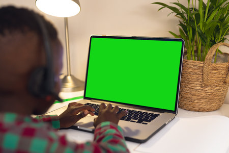 Rear view of african american boy using laptop while having a video call on laptop with copy space....