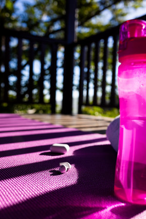 Vertical image of balcony of log cabin with bottle of water, towel, earphones and mat on sunny day. Nature, agriculture, summer, tranquillity and activity.の写真素材