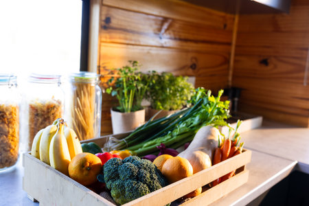 Crate of organic vegetables on countertop in sunny kitchen in log cabin. Food, nutrition, balanced...