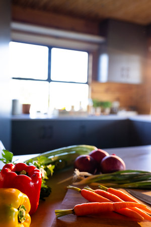 Vertical image of organic vegetables on cutting board and knife in sunny kitchen in log cabin. Food, nutrition, balanced diet and healthy living.の写真素材