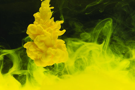 Close up of bright yellow ink in water with copy space on black background. Ink, liquid, shape and...