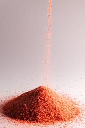 Close up of orange sand pouring into heap and copy space on white background. Sand, texture,...