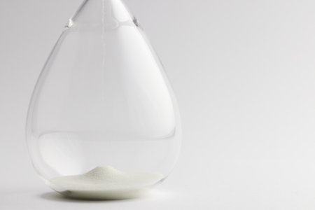 Close up of hourglass with white sand and copy space on white background. Time, timekeeping, shape and colour concept.の写真素材