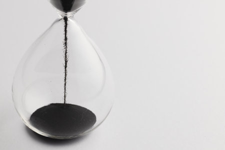 Close up of hourglass with black sand and copy space on white background. Time, timekeeping, shape...