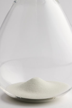 Close up of hourglass with white sand and copy space on white background. Time, timekeeping, shape...