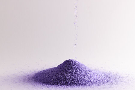 Close up of purple sand pouring into heap and copy space on white background. Sand, texture, movement, shape and colour concept.の写真素材