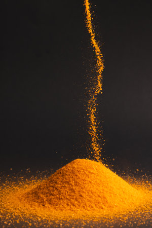 Close up of orange sand pouring into heap and copy space on black background. Sand, texture, movement, shape and colour concept.の写真素材