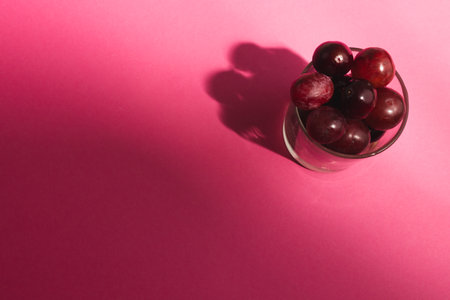 Close up of glass of red grapes and copy space on pink background. Fruit, food, freshness and colour concept.の写真素材