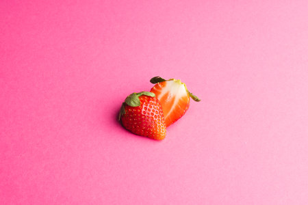Close up of halved strawberry and copy space on pink background. Fruit, berry, food, freshness and colour concept.の写真素材