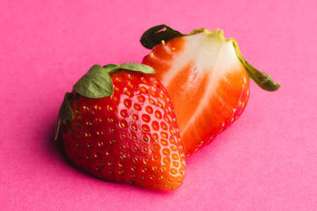 Close up of halved strawberry and copy space on pink background. Fruit, berry, food, freshness and...