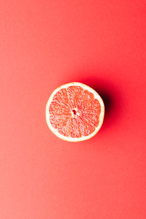 Close up of half of red grapefruit and copy space on red background. Fruit, food, freshness and...