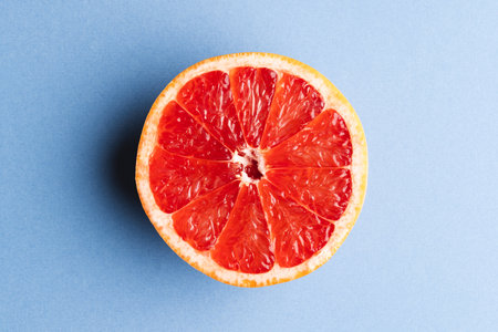 Close up of half of red grapefruit and copy space on blue background. Fruit, food, freshness and colour concept.の写真素材