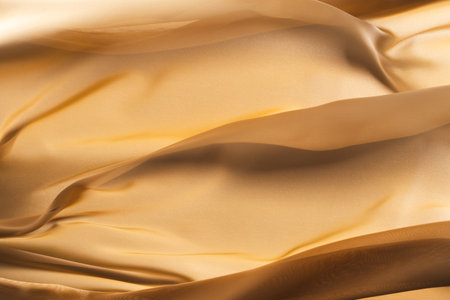 Close up of gold shiny silk fabric with copy space background. Texture, fabric, cloth, colour and material.の写真素材