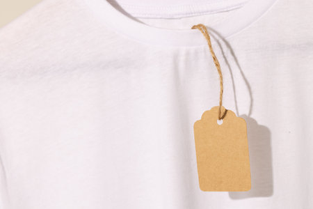 White t shirt with tag with copy space on white background. Fashion, clothes, colour and fabric...