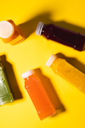 Close up of plastic bottles with fresh juice and copy space on yellow background. Fruit, drink, food, freshness and colour concept.の写真素材