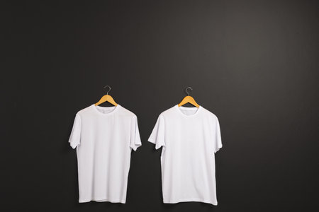 Two white t shirts on hangers and copy space on black background. Fashion, clothes, colour and fabric concept.の写真素材