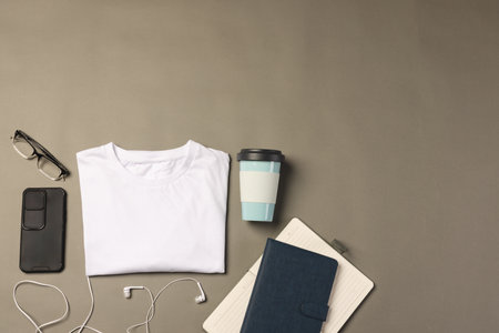 Flat lay of white t shirt, smartphone, earphones and notebooks with copy space on grey background. Fashion, clothes, colour and fabric concept.の写真素材
