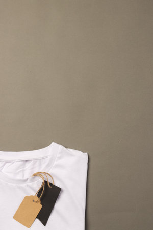 Folded white t shirt with tags with copy space on brown background. Fashion, clothes, colour and fabric concept.の写真素材