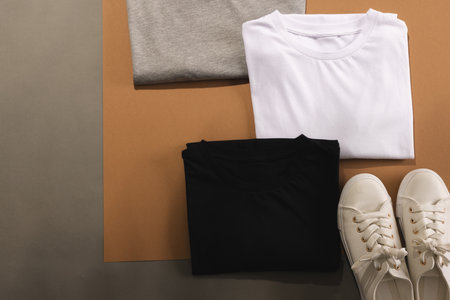 Close up of folded t shirts and white sneakers and copy space on brown background. Fashion, clothes, colour and fabric concept.の写真素材