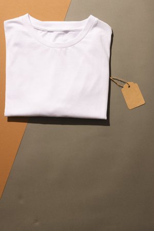 Close up of folded white t shirt with tag and copy space on brown background. Fashion, clothes,...