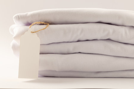 Stack of white t shirts with tag and copy space on white background. Fashion, clothes, colour and fabric concept.の写真素材