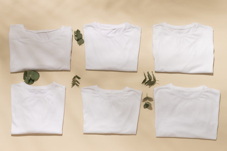 Close up of folded white t shirts with leaves and copy space on yellow background. Fashion, clothes, colour and fabric concept.の写真素材