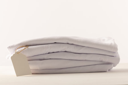 Stack of white t shirts with tag and copy space on white background. Fashion, clothes, colour and fabric concept.の写真素材