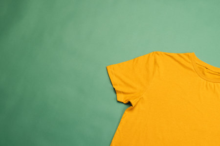 Orange t shirt and copy space on green background. Fashion, clothes, colour and fabric concept.の写真素材