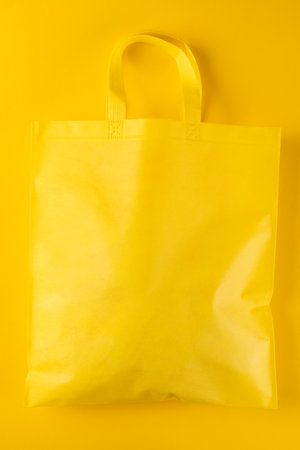 Close up of yellow canvas bag with copy space on yellow background. Shopping, bag, colour, fabric, texture and materials concept.の写真素材