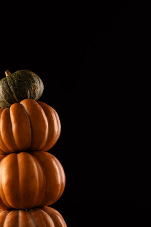 Orange and green pumpkins stacked up with copy space on black background. Halloween, colour, movement and smoke concept.の写真素材