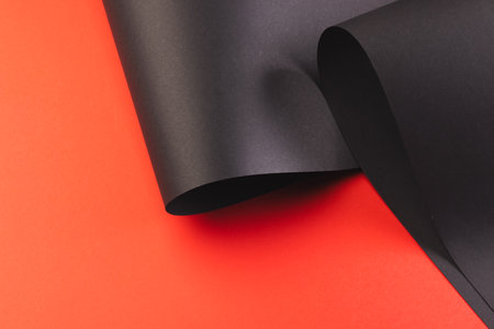 Close up of rolled up pieces of black paper with copy space on red background. Paper, writing, texture and materials concept.の写真素材