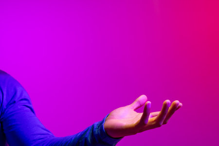 Hand of caucasian businessman with copy space on neon pink to purple background. Technology, digital...