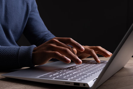 Biracial businessman using laptop with copy space on black background. Technology, digital networks, global connections and communication metaverse.の写真素材
