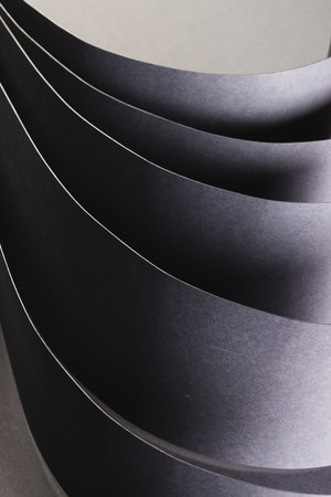 Vertical image of close up of rolled up pieces of black paper with copy space on grey background. Paper, writing, texture and materials concept.の写真素材